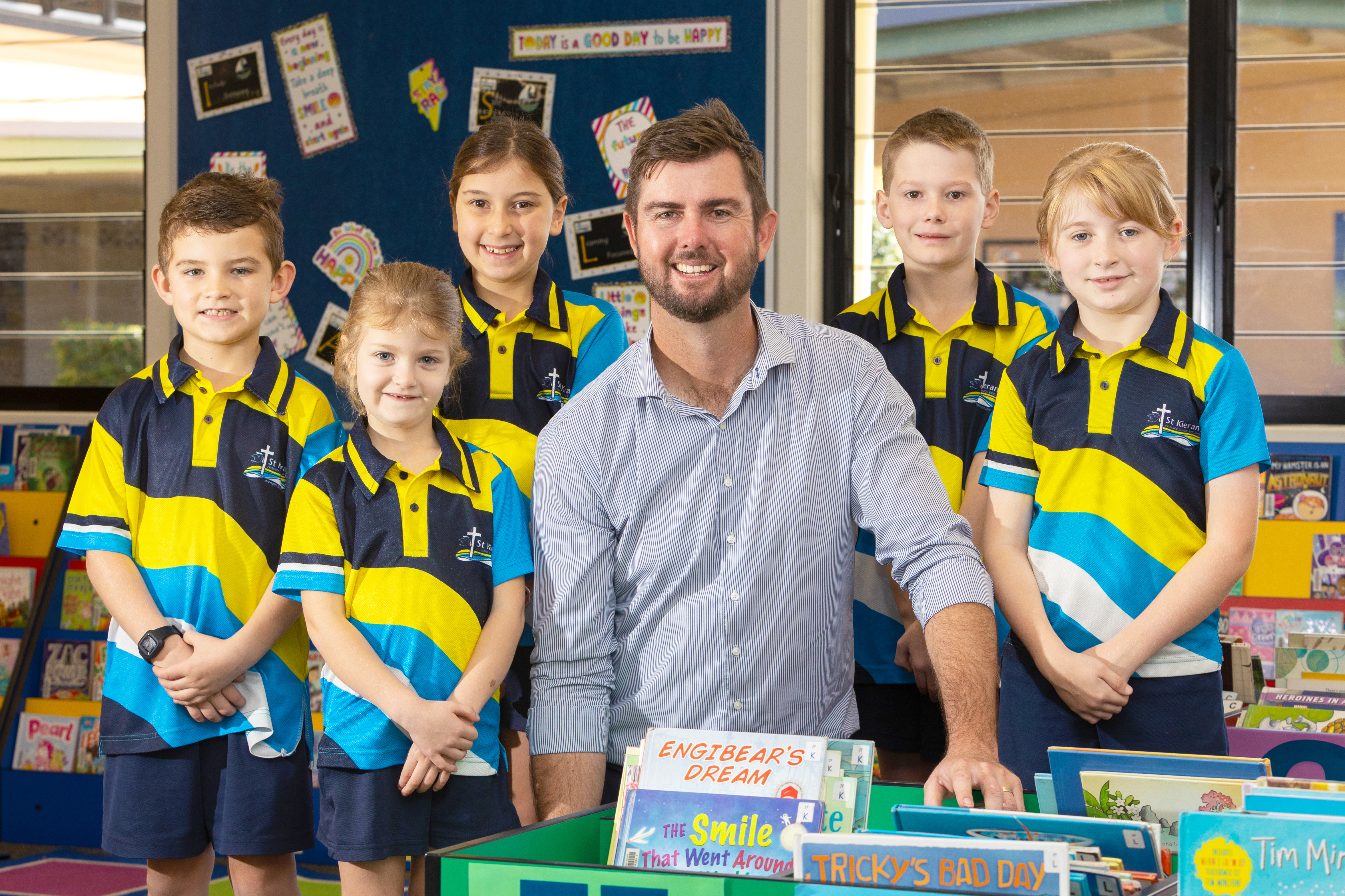 Mr Ben Gray, Principal, standing with a group of students in school uniforms in a library setting